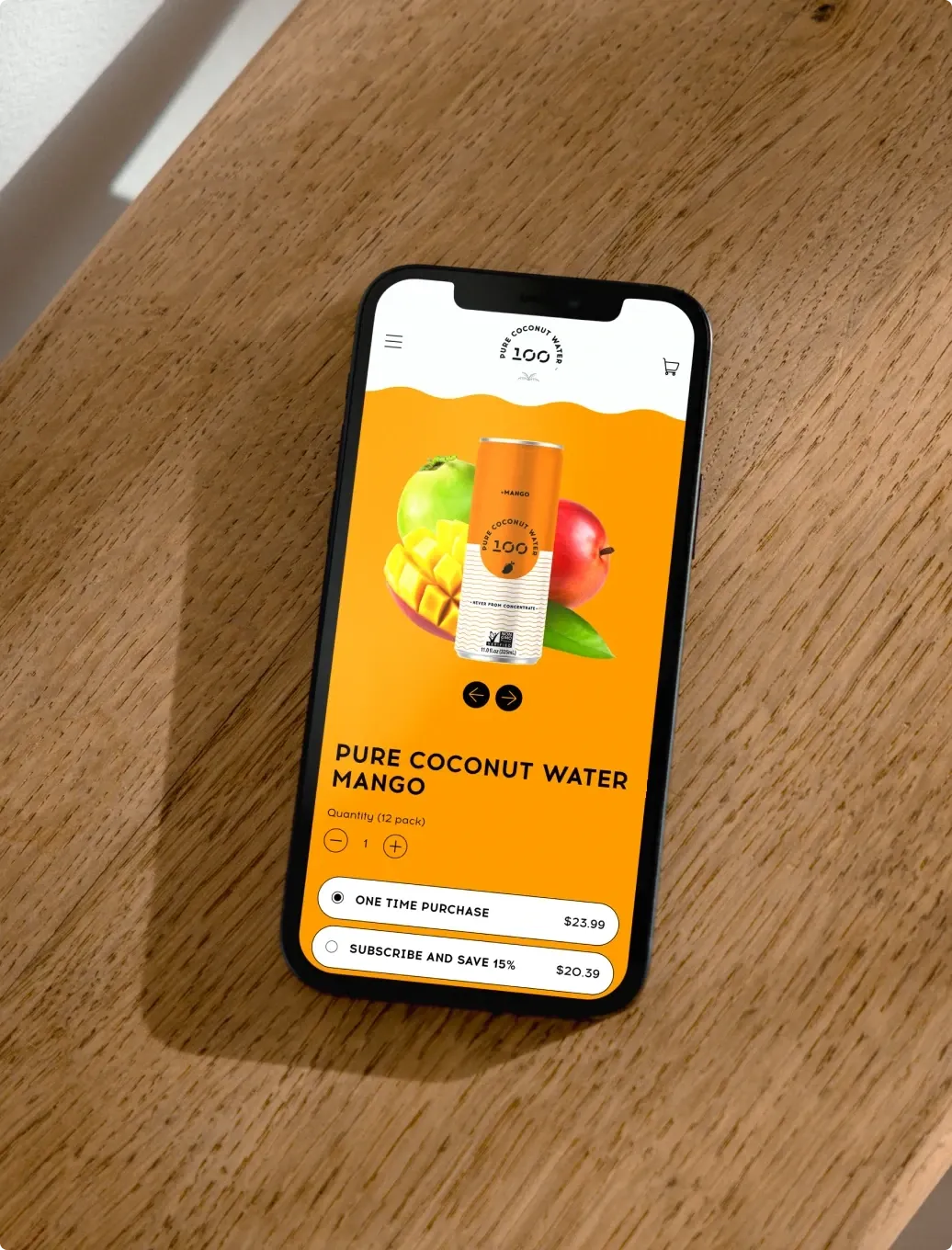 A phone on a wooden table open on the 100 Coconuts mango product page.