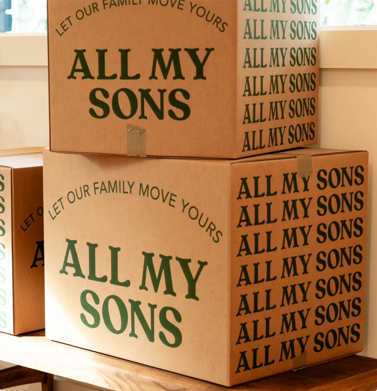 Two All My Sons boxes in the new branding, stacked in a sunny room.