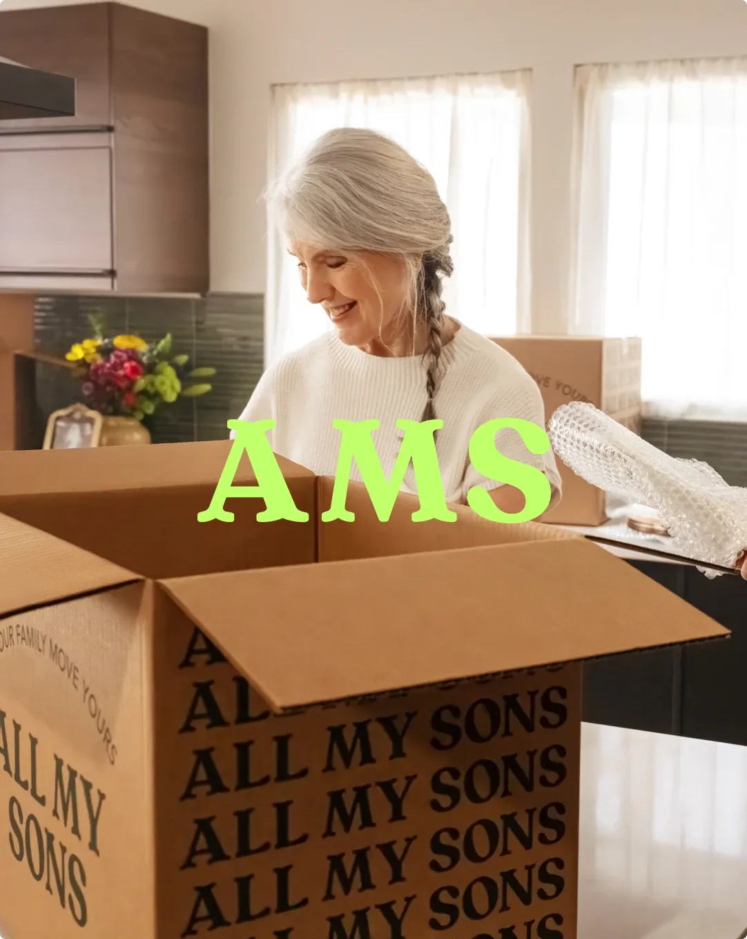 A woman smiling as she unpacks an All My Sons box in her kitchen.