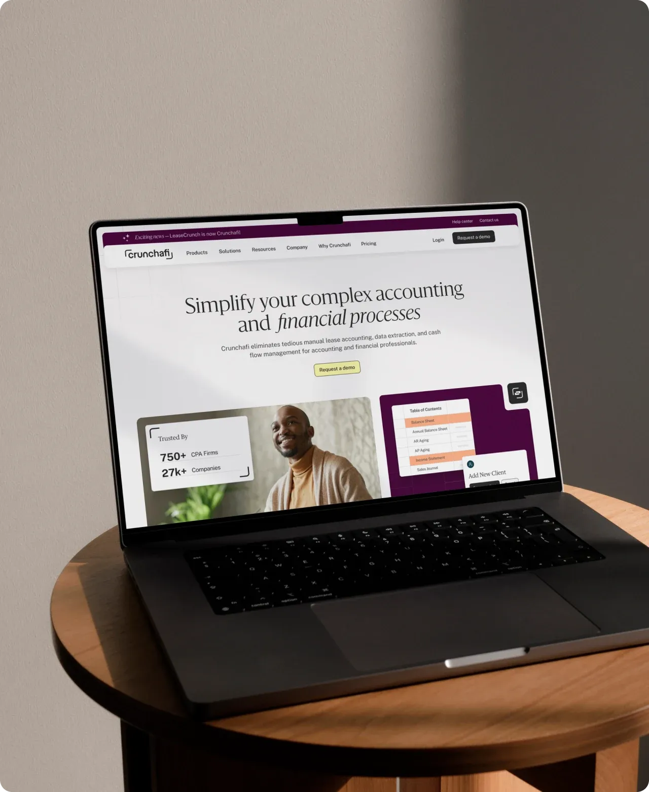 The Crunchafi website open on a laptop on a wooden side table, its headline reading "Simplify your complex accounting and financial processes".
