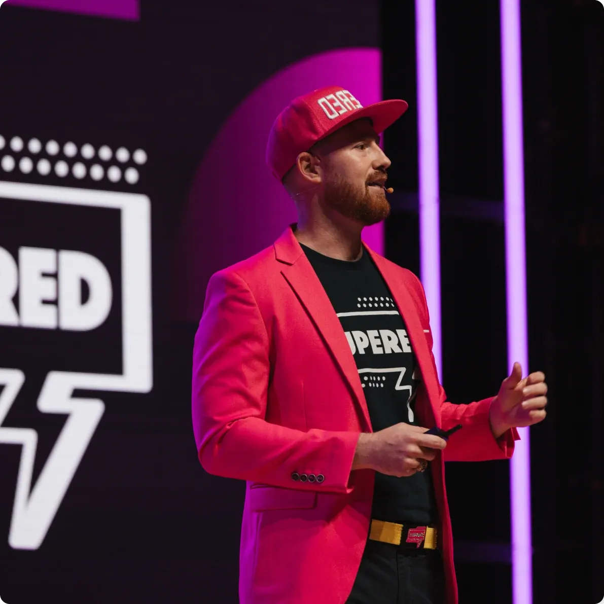 A speaker in a red jacket and cap on the Venture Atlanta stage.