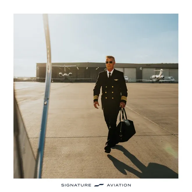 A pilot crossing the apron with his flight bag, framed in a Signature Aviation ad.