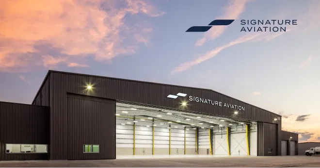 A Signature Aviation hangar under a pink evening sky.