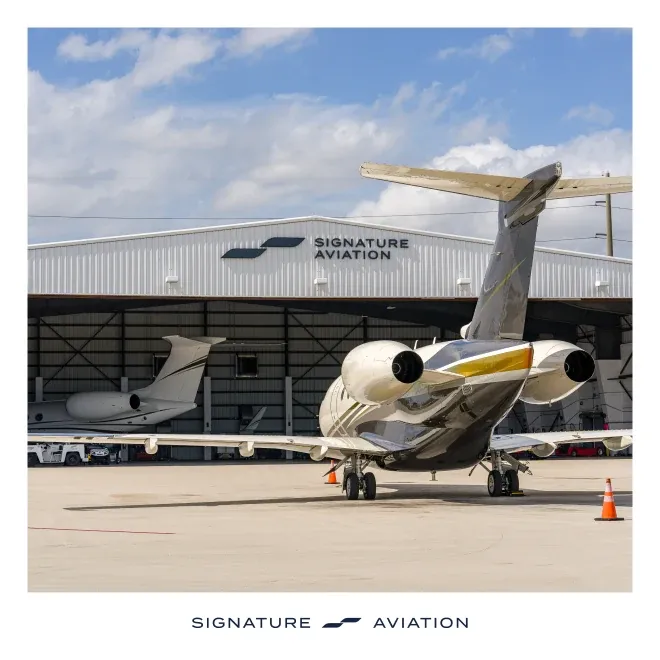A private jet parked outside a Signature Aviation hangar.
