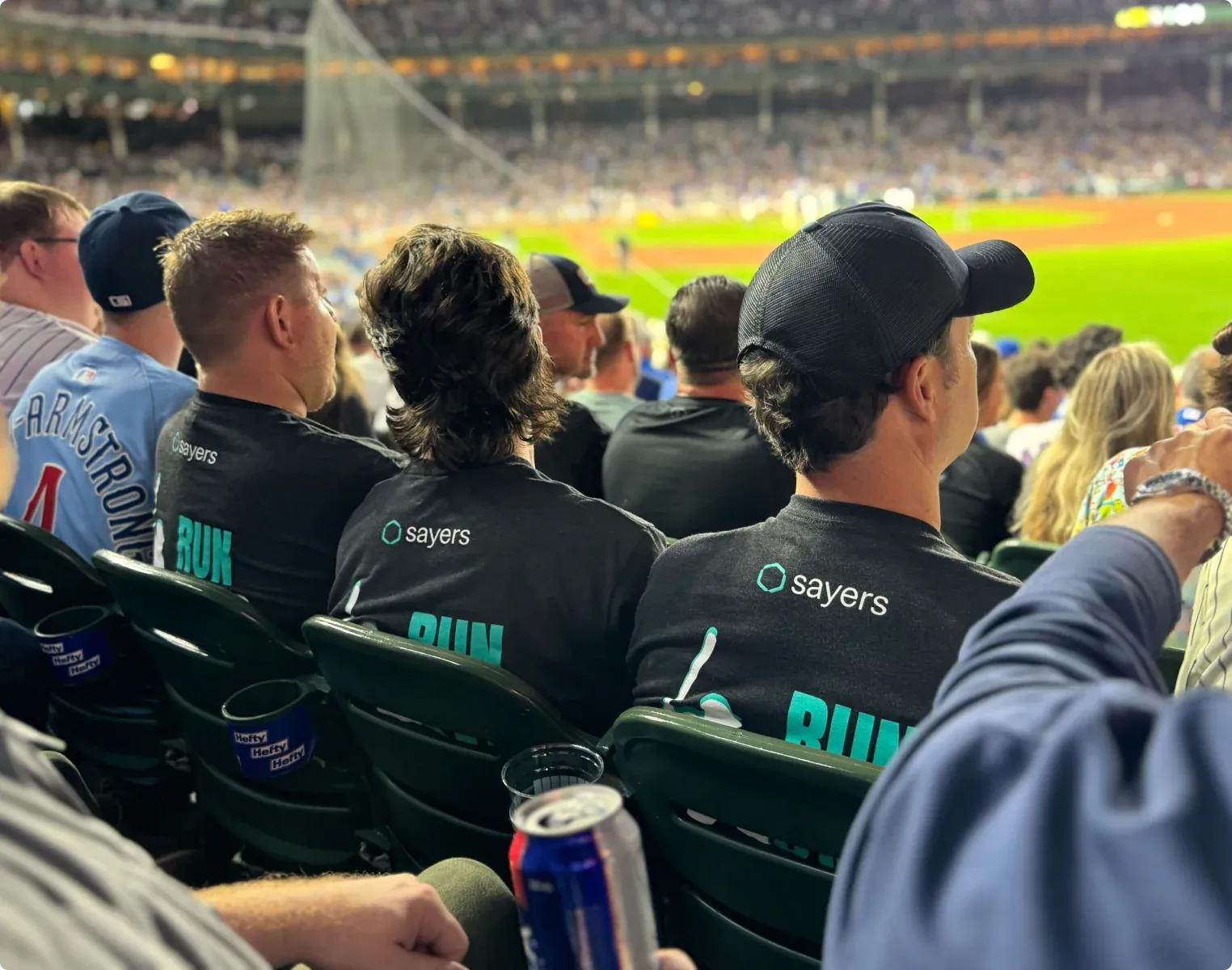 The Sayers team at a baseball game in matching black Sayers shirts.