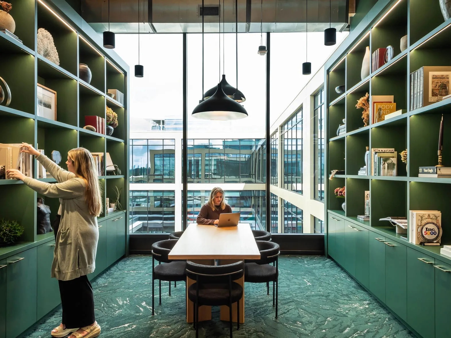 A colleague taking a book from the green shelves of the studio library