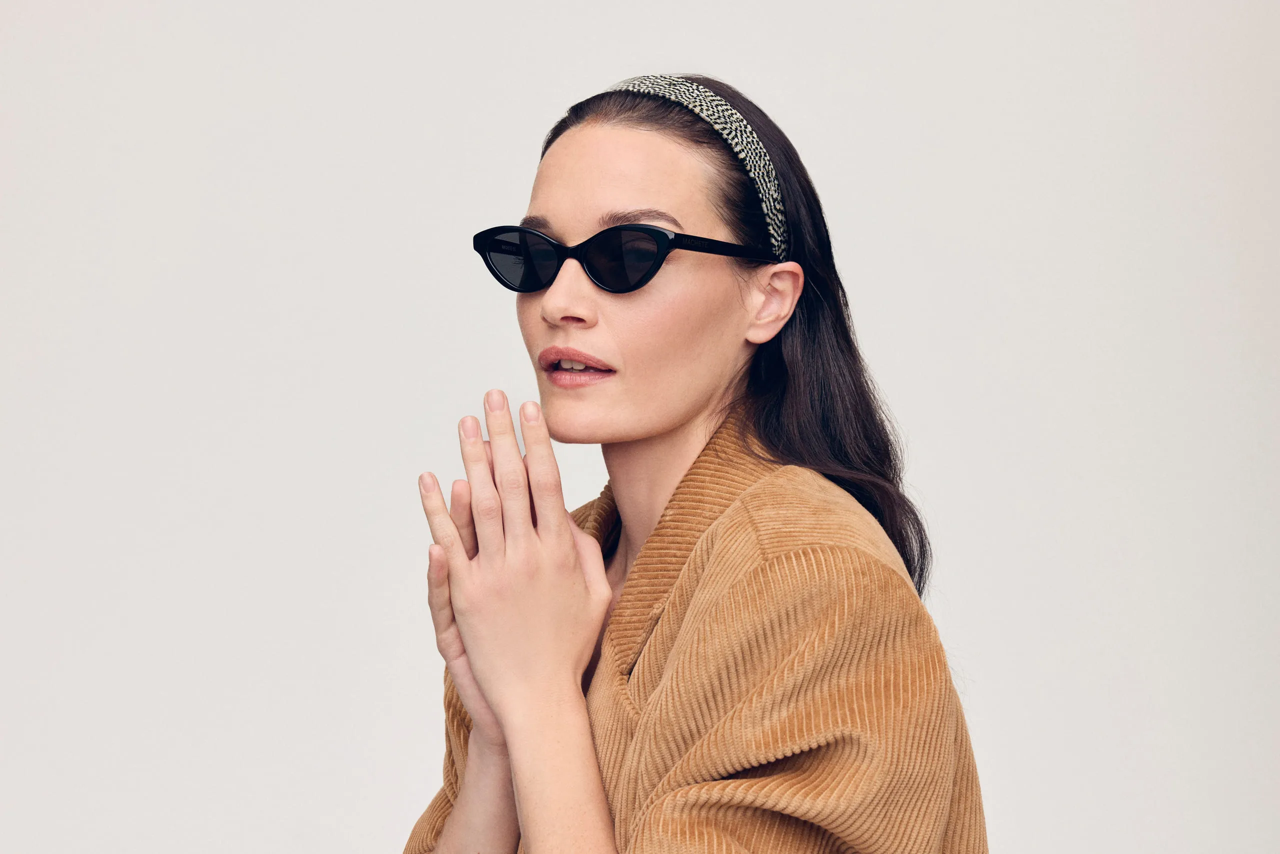 A model in a corduroy jacket wearing Machete cat-eye sunglasses and a beaded headband.