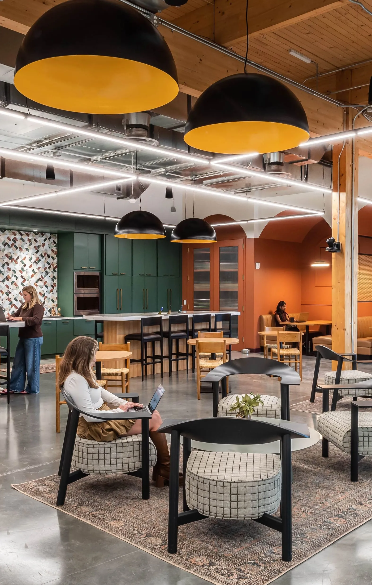 The open-plan studio under big pendant lights, colleagues at work at the tables