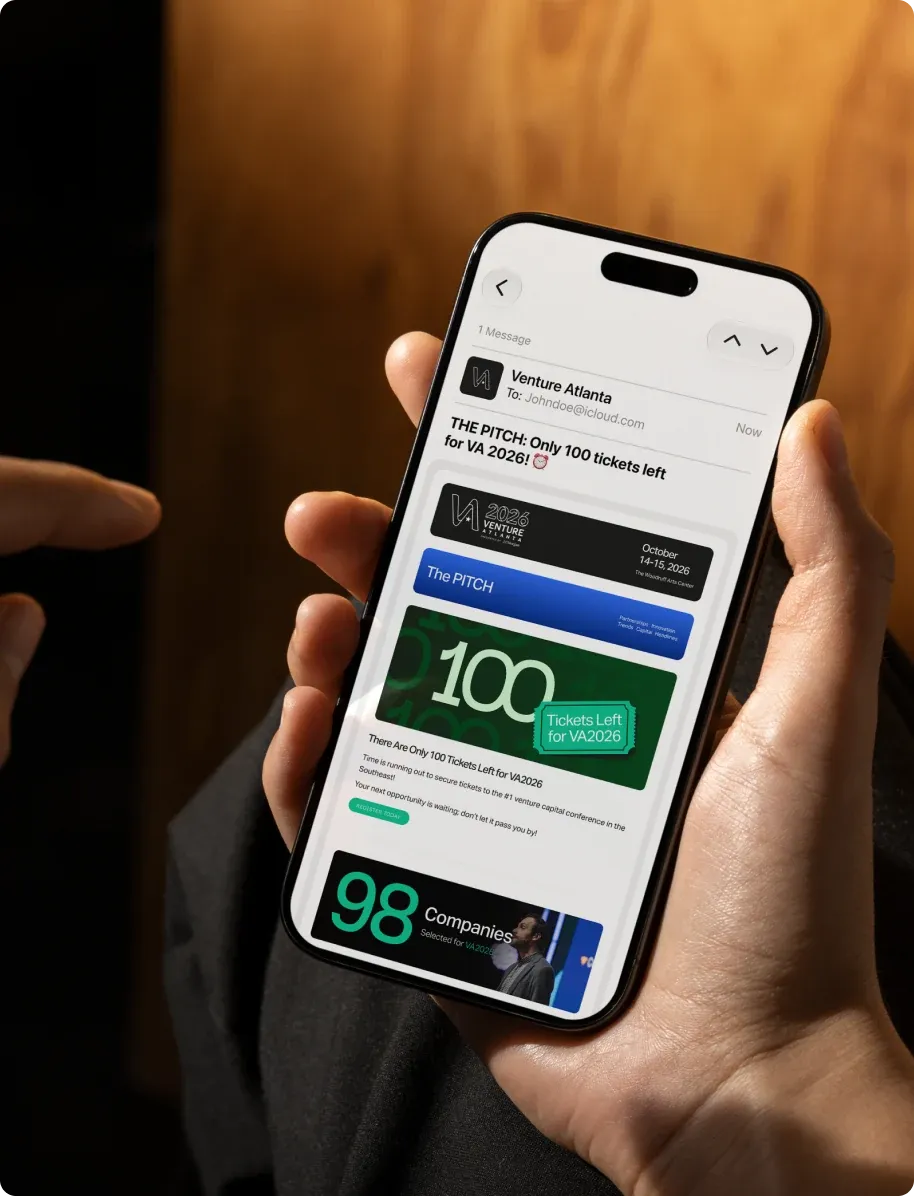 A hand holding a phone open on a Venture Atlanta email announcing 100 selected companies.