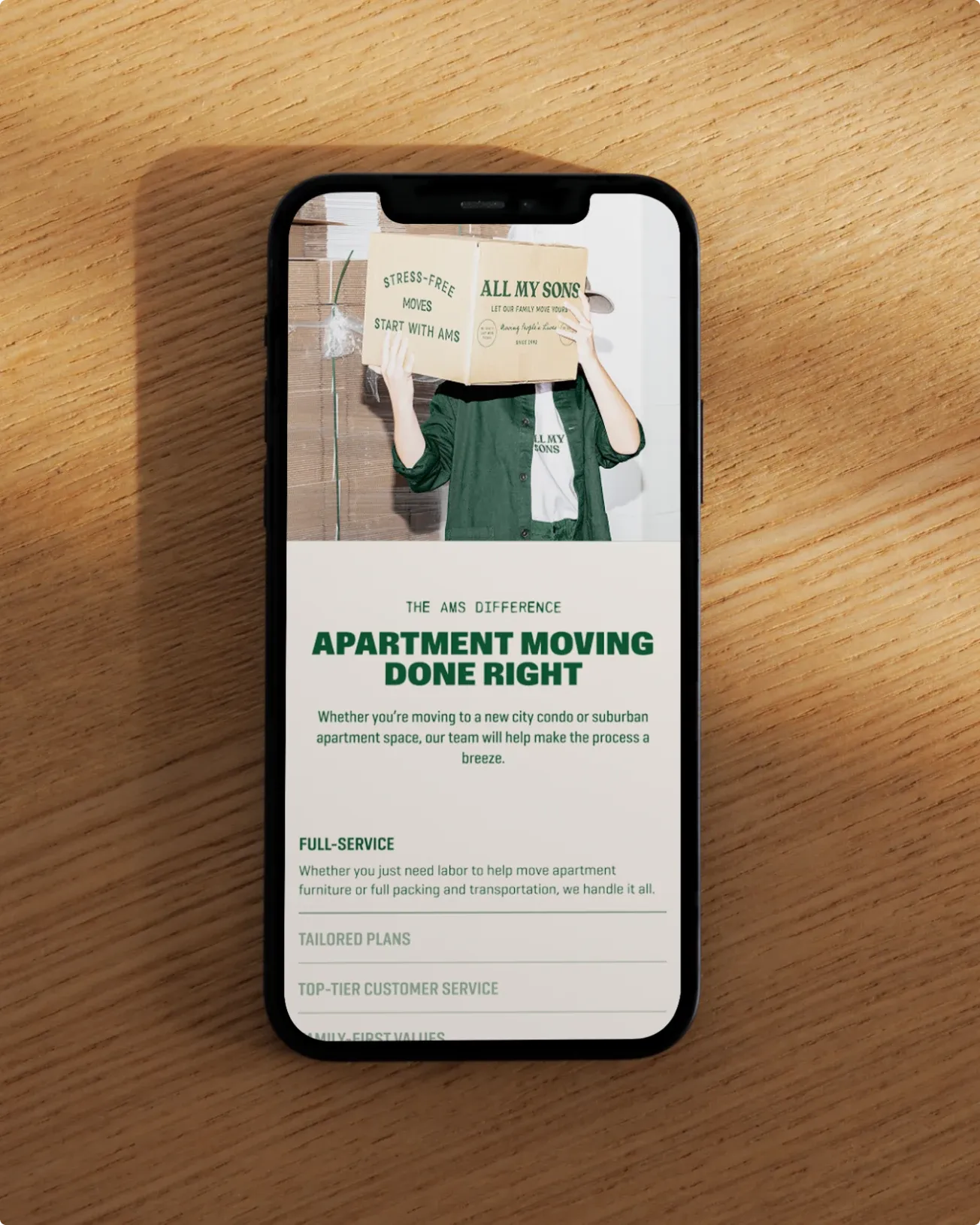 The All My Sons apartment moving page on a phone lying on a wooden table.